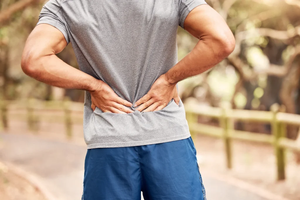 man holding lower back outdoors on path 2026 03 25 03 56 35 utc