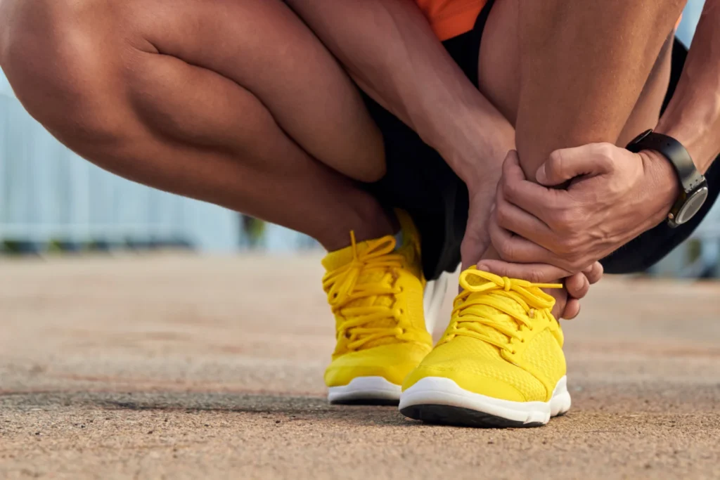 person tying bright yellow athletic shoe outdoors 2026 04 13 02 08 16 utc