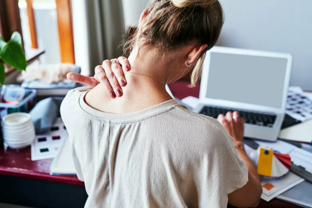 woman massaging her shoulder while working at desk 2026 01 09 09 56 12 utc